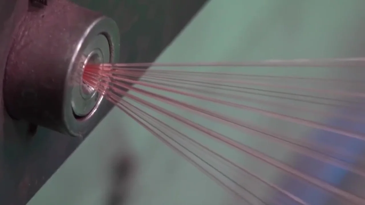 Wire drawing line — fine copper strands running through the drawing dies